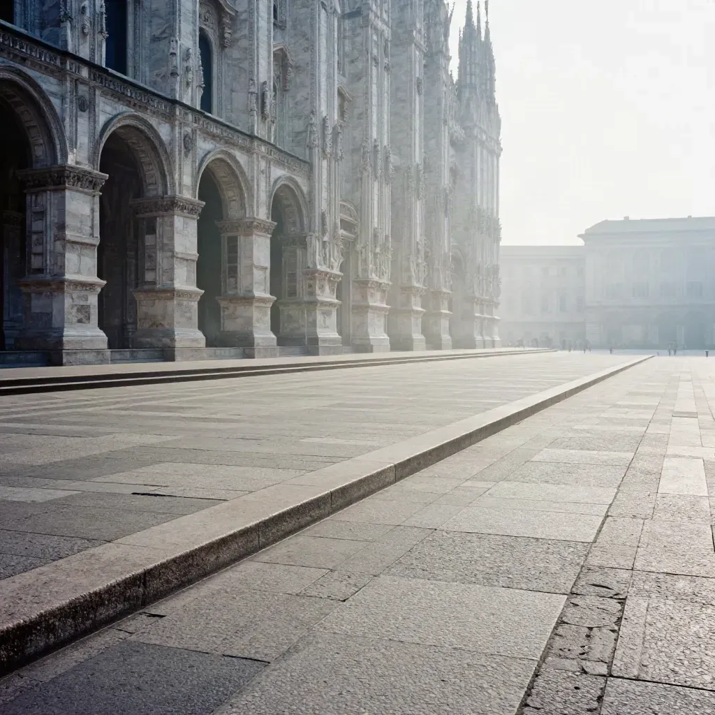 Arcate in pietra di Milano e guglie del Duomo nella nebbia sopra una piazza calma.