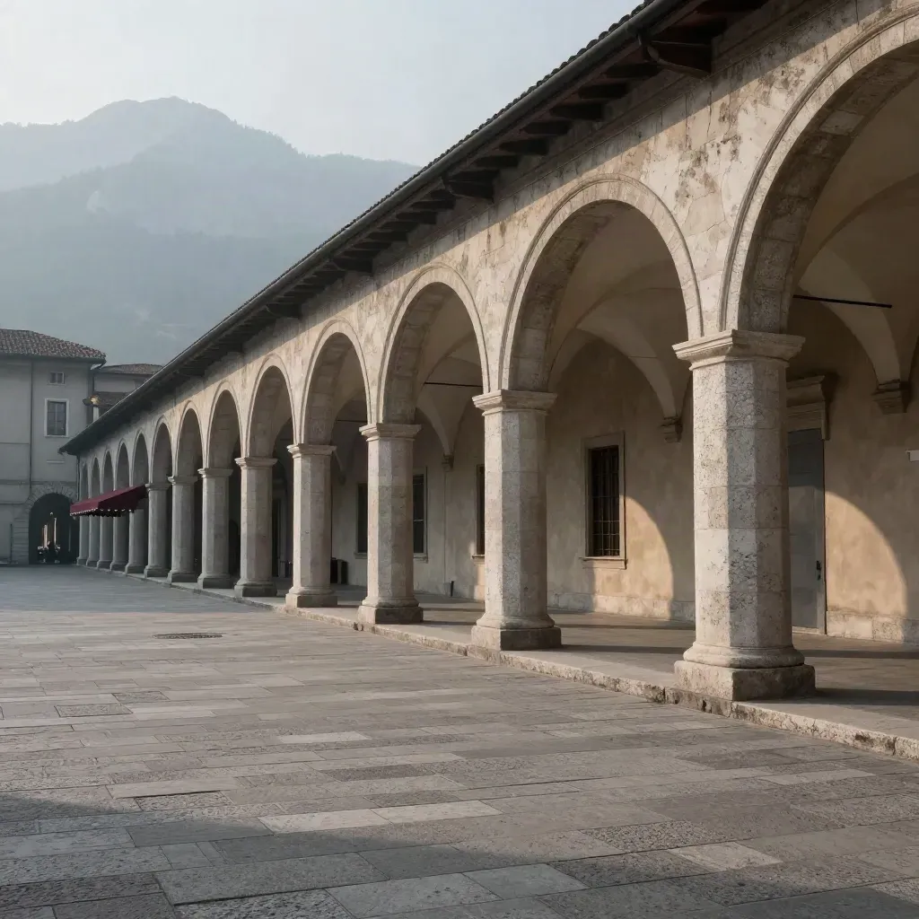 Portici di Torino e Alpi lontane sopra una piazza di pietra in luce serale.